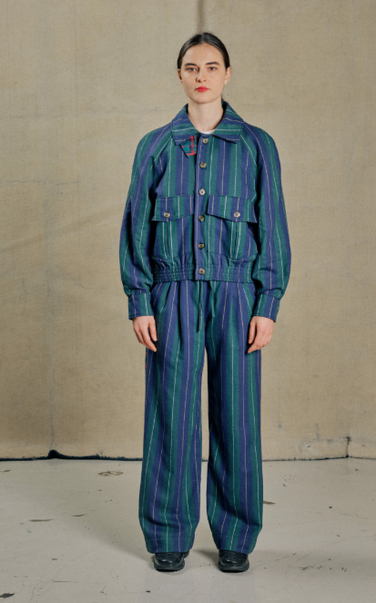 Mannequin qui pose avec un esmeble d'une veste et un pantalon avec une coupe très ample. Le motif est en rayures voilettes et vertes
