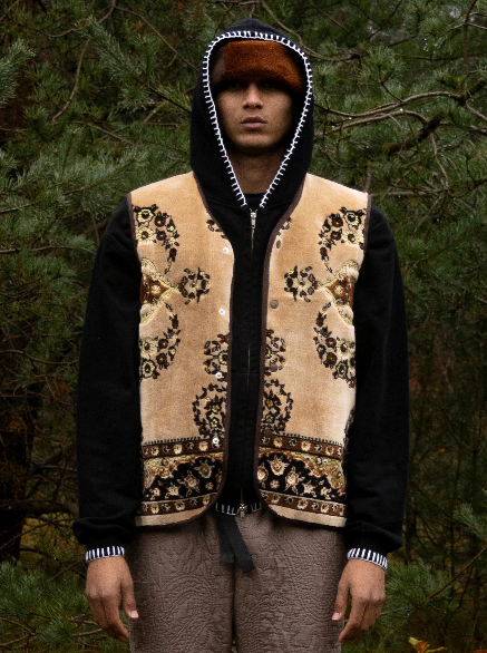 Mannequin avec un hoodie noir et un gilet issu de l'upcycling au-dessus. Le gilet est fait à partir de tapis. Le motif est noir sur un fond marron clair.
