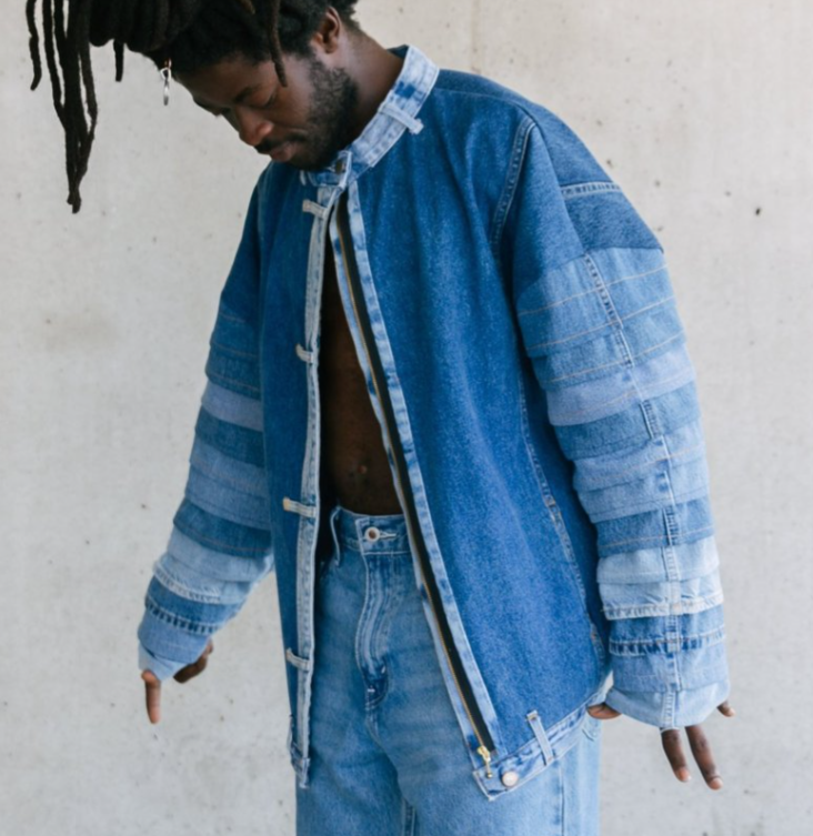 Veste en jean recyclé avec des rayures de differentes teintes de jeans sur les manches.